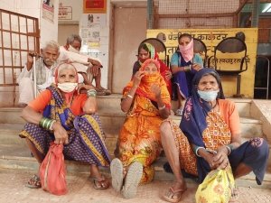 कोरोना का टीका लगवाने अस्पताल परिसर में बैठी बुजुर्ग महिलाएं।